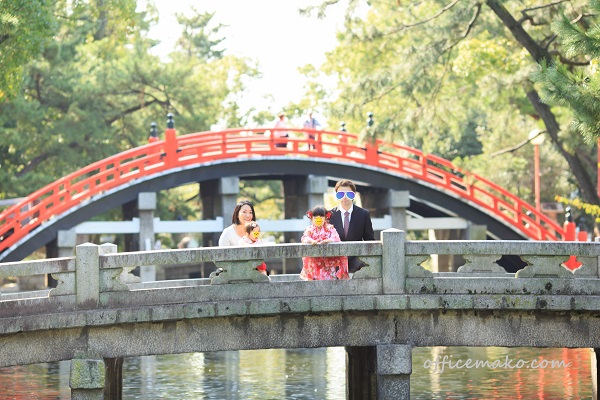 神社の橋の上で家族写真を撮っている写真です