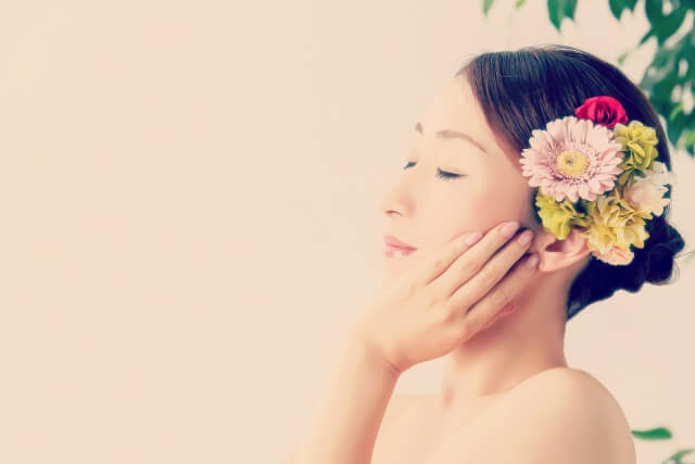 目を閉じて頬に手を当てている女性