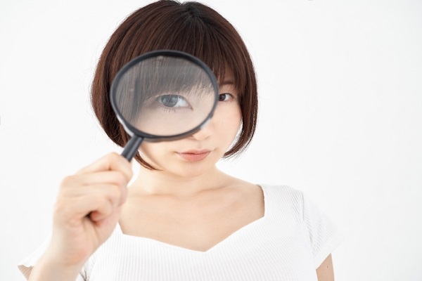 虫眼鏡を覗く女性の画像