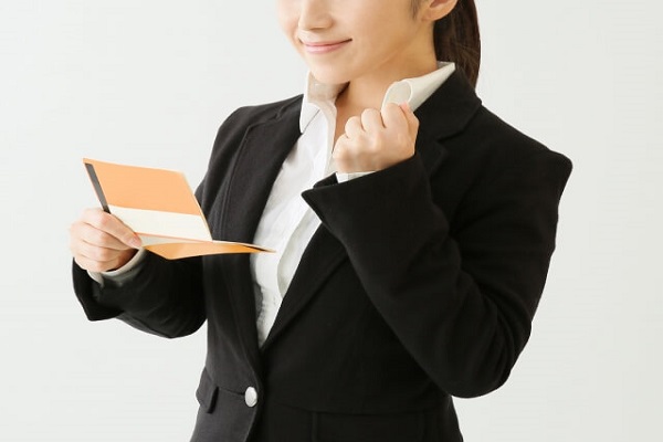 通帳を見てガッツポーズをする女性の画像