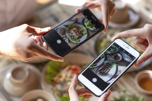 スマホで料理の写真を撮っている画像