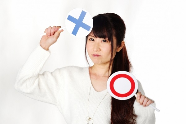 丸とばつの札を持っている女性の画像