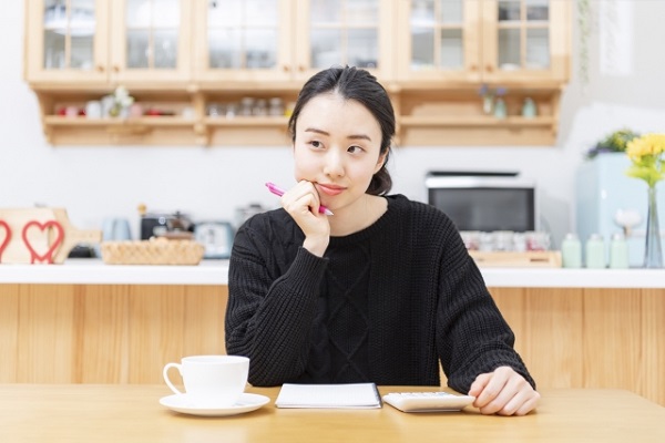 ペンを持って考えている女性の画像