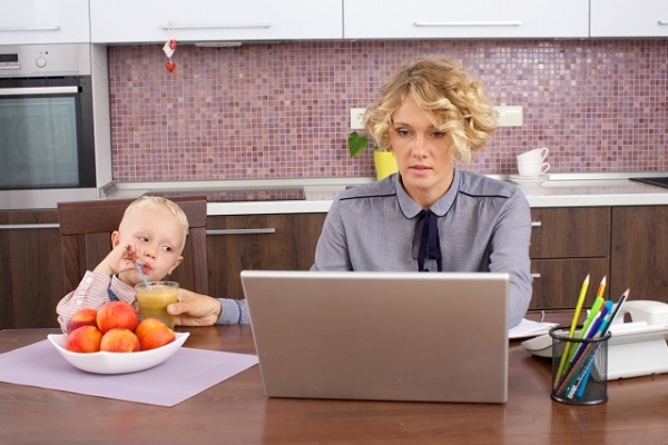 子供のお世話をしながら、パソコンに向かう女性の画像