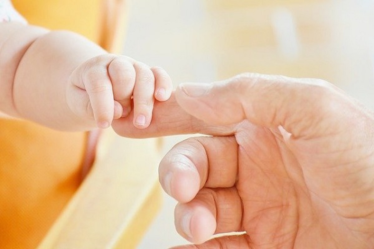 赤ちゃんの手がお父さんの手に触れている画像