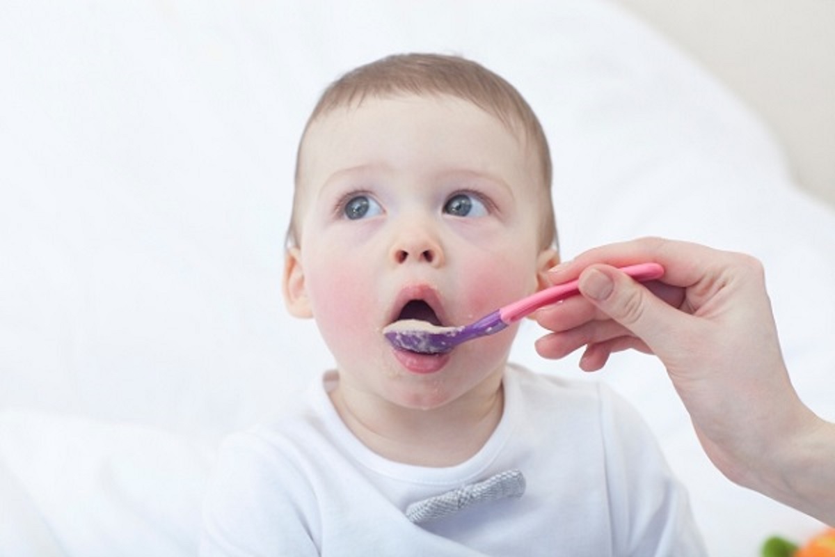 スプーンにのった離乳食を食べる赤ちゃんの画像